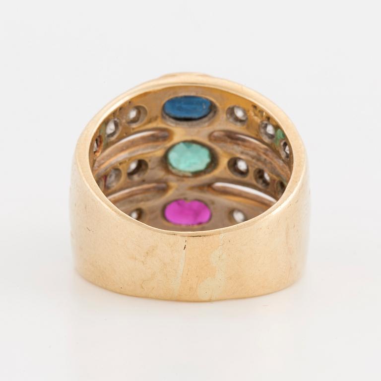 An oval cut ruby, sapphire and emerald ring, surrounded by brilliant cut diamonds.