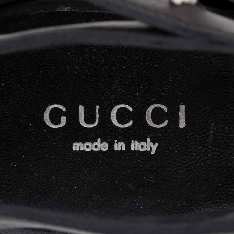 GUCCI, a pair of black leather strap sandals.