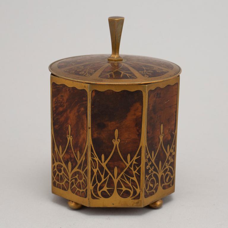 An art nouveau brass and burr walnut tobacco jar and cover from around year 1900.