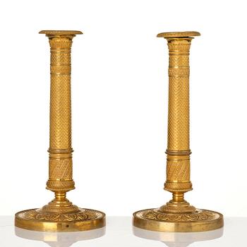 A pair of French Empire ormolu candlesticks, early 19th century.