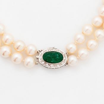 A two strand cultured pearl necklace with an 18K white gold and emerald clasp.