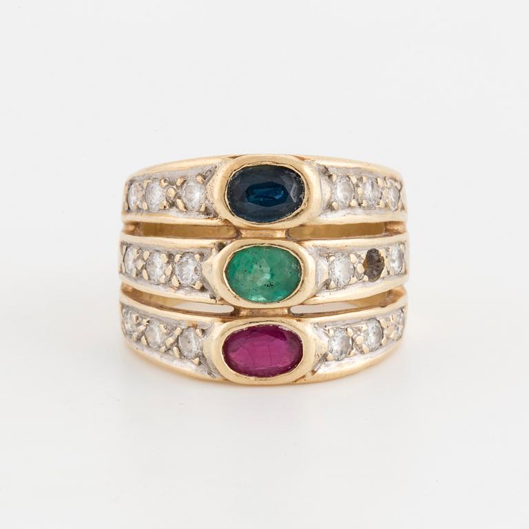 An oval cut ruby, sapphire and emerald ring, surrounded by brilliant cut diamonds.