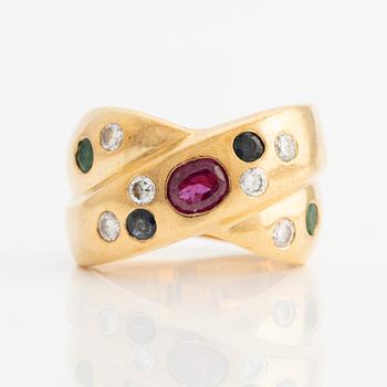 Ring in 18K gold with a faceted ruby, emerald, sapphire, and round brilliant-cut diamonds.