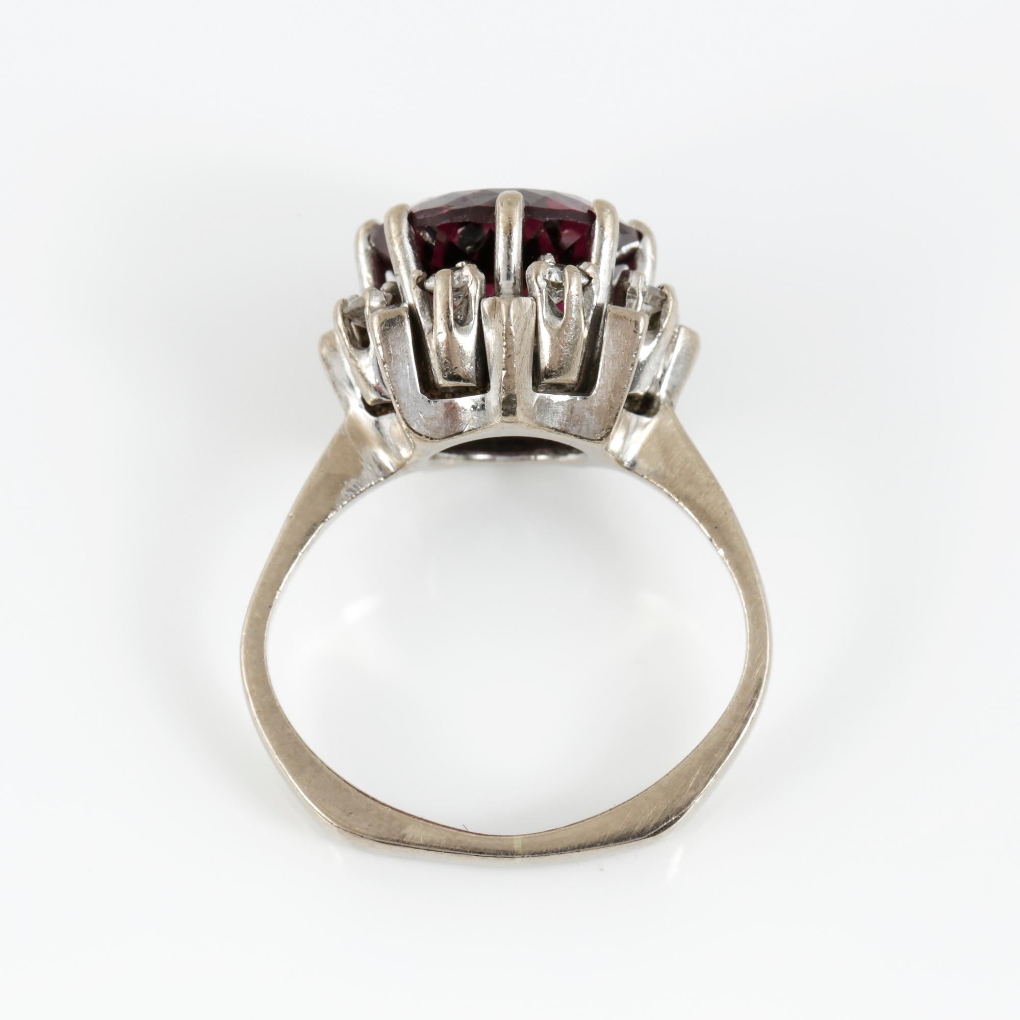 RING, 18K vitguld med fasetterad granat tot ca 3,68 cts omgiven av briljantslipade diamanter tot ca 0,4 ct. Vikt 6,91 g.