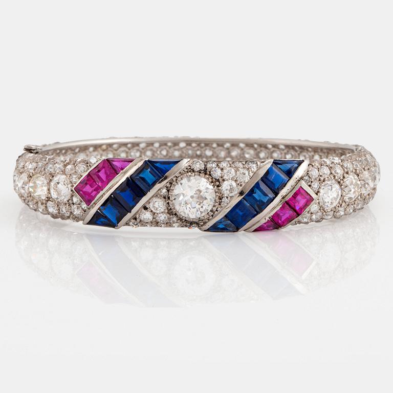 A platinum bangle set with old- and rose-cut diamonds and faceted sapphires and rubies.