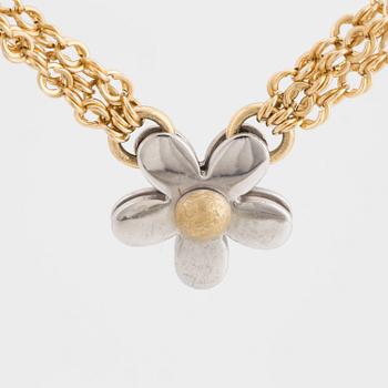 A three stranded chain necklace with a pendant in the shape of a flower.