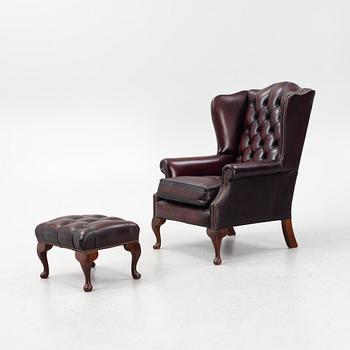 A leather upholstered wingback chair with stool. end of the 20th Century.
