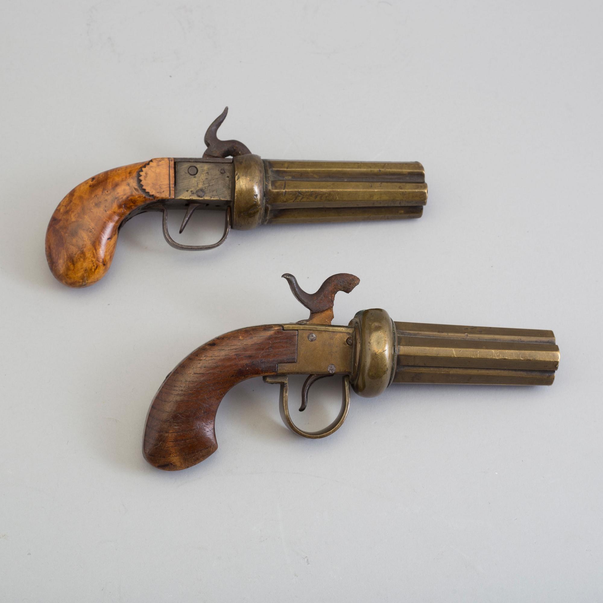 SLAGLÅSREVOLVRAR, 2 st, svenska, i mässing, fyrpipiga, varav 1 signerad.