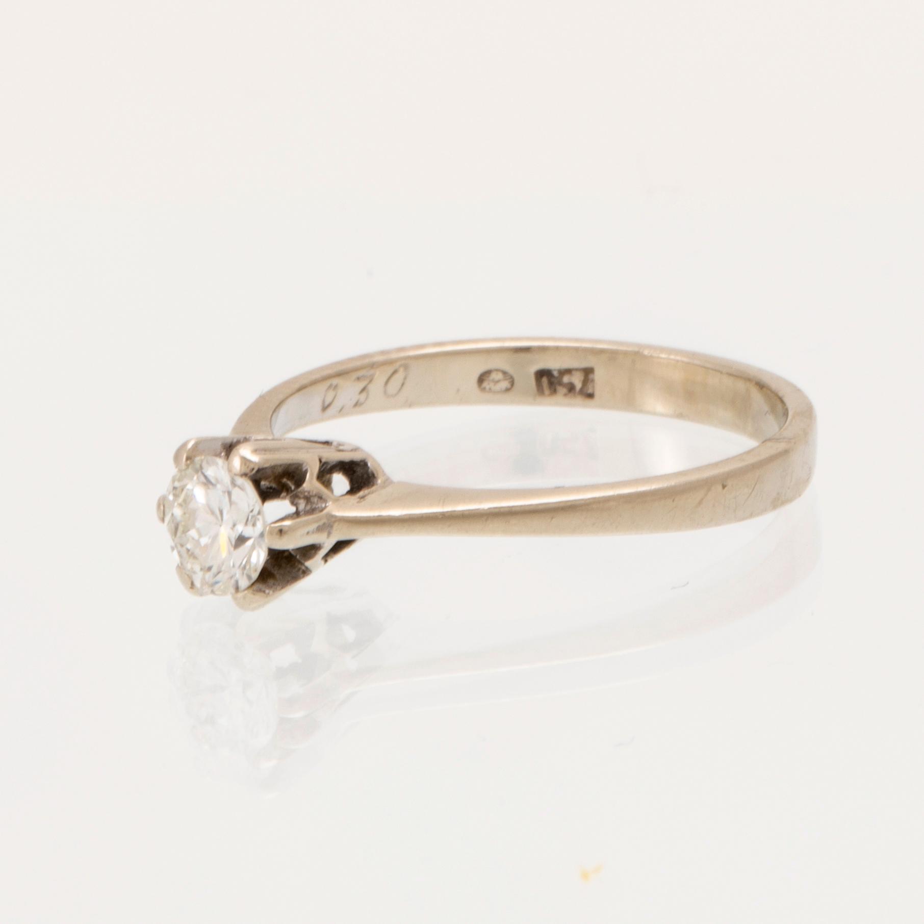 An 18K white gold solitaire ring set with a round brilliant-cut diamond.