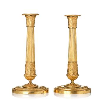 175. A pair of French Empire ormolu candlesticks, early 19th century.