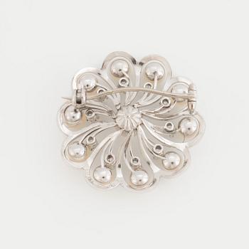 A brooch set with cultured pearls and round, brilliant-cut diamonds.