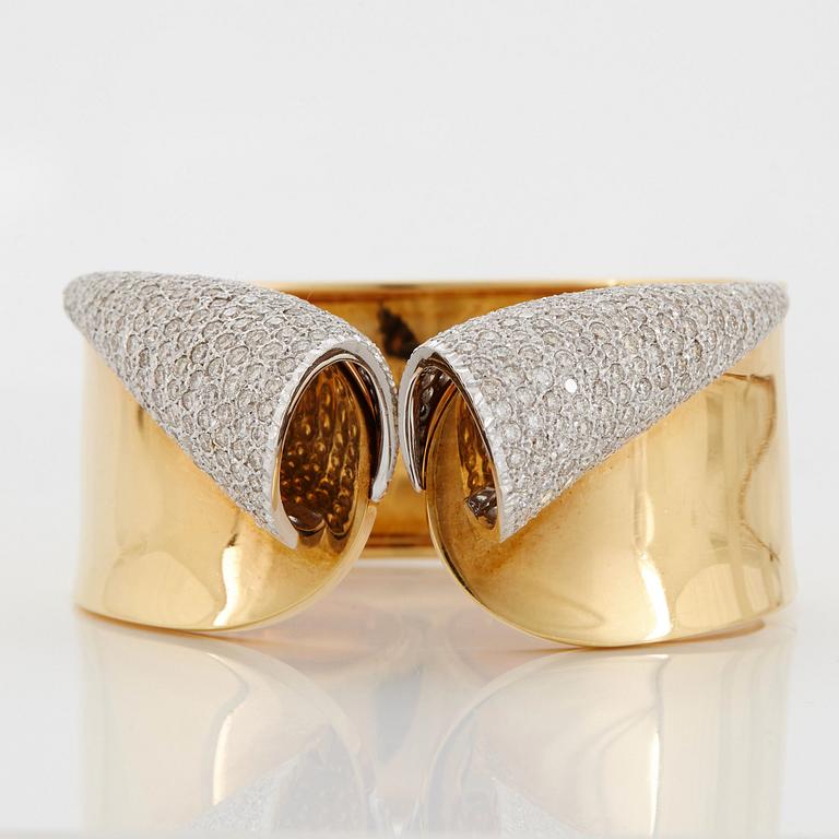 An 18K gold bangle set with round brilliant-cut diamonds.