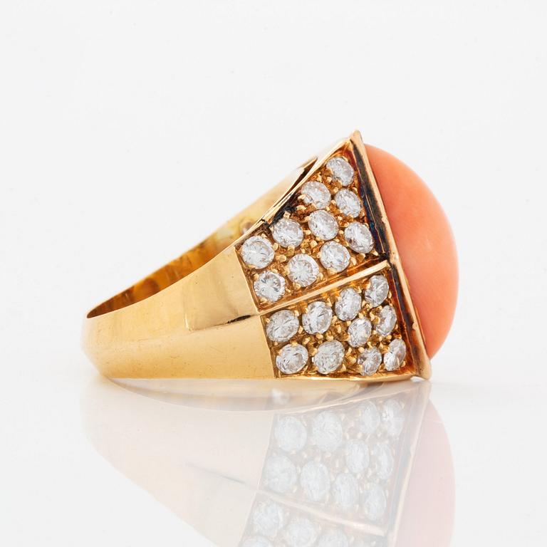 An 18K gold and coral ring set with round brilliant-cut diamonds.