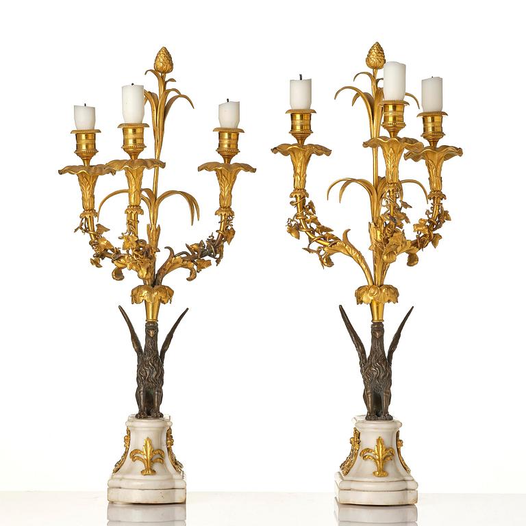 A pair of three-light Louis XVI patinated and ormolu candelabra in the manner of François Rémond, late 18th century.