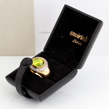 An 18K gold Steinlin ring set with a cabochon-cut peridot and round brilliant-cut diamonds.