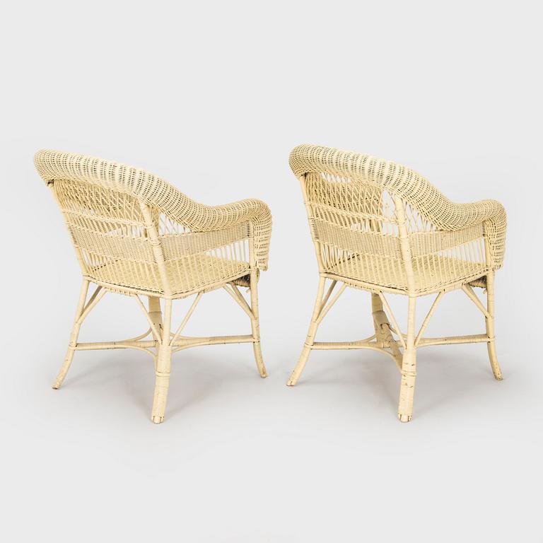 A mid-20th-century three-piece rattan furniture set including two armchairs, and a table.