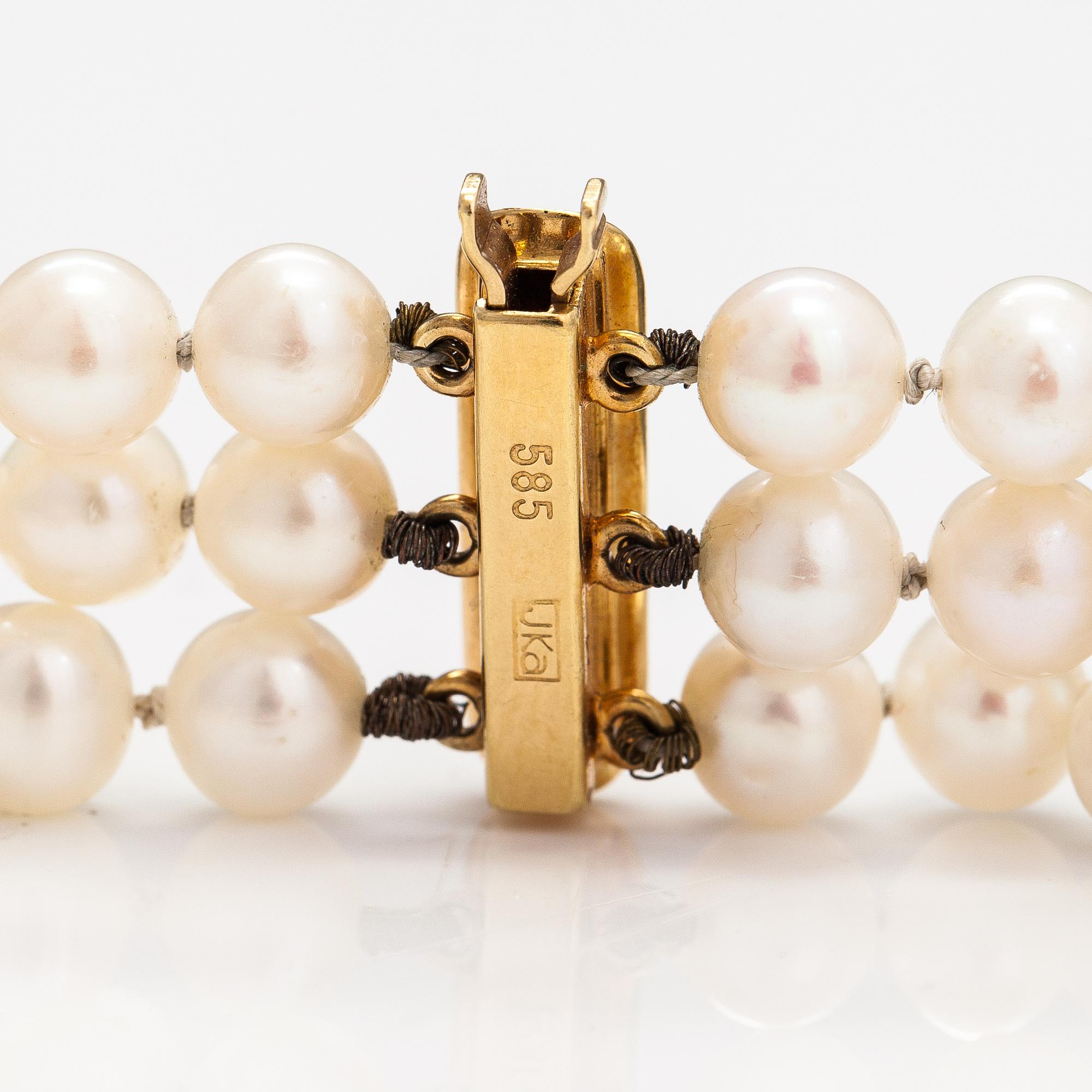 A three-strand cultured pearl collier with an amethyst and 14K gold.