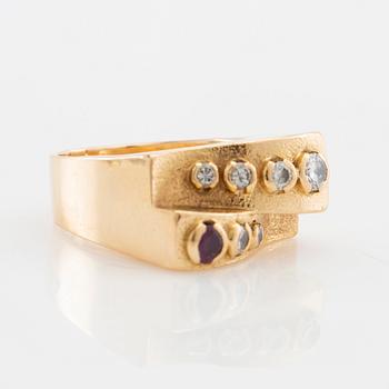 Ring in 18K gold set with round brilliant-cut diamonds and a round faceted gemstone.