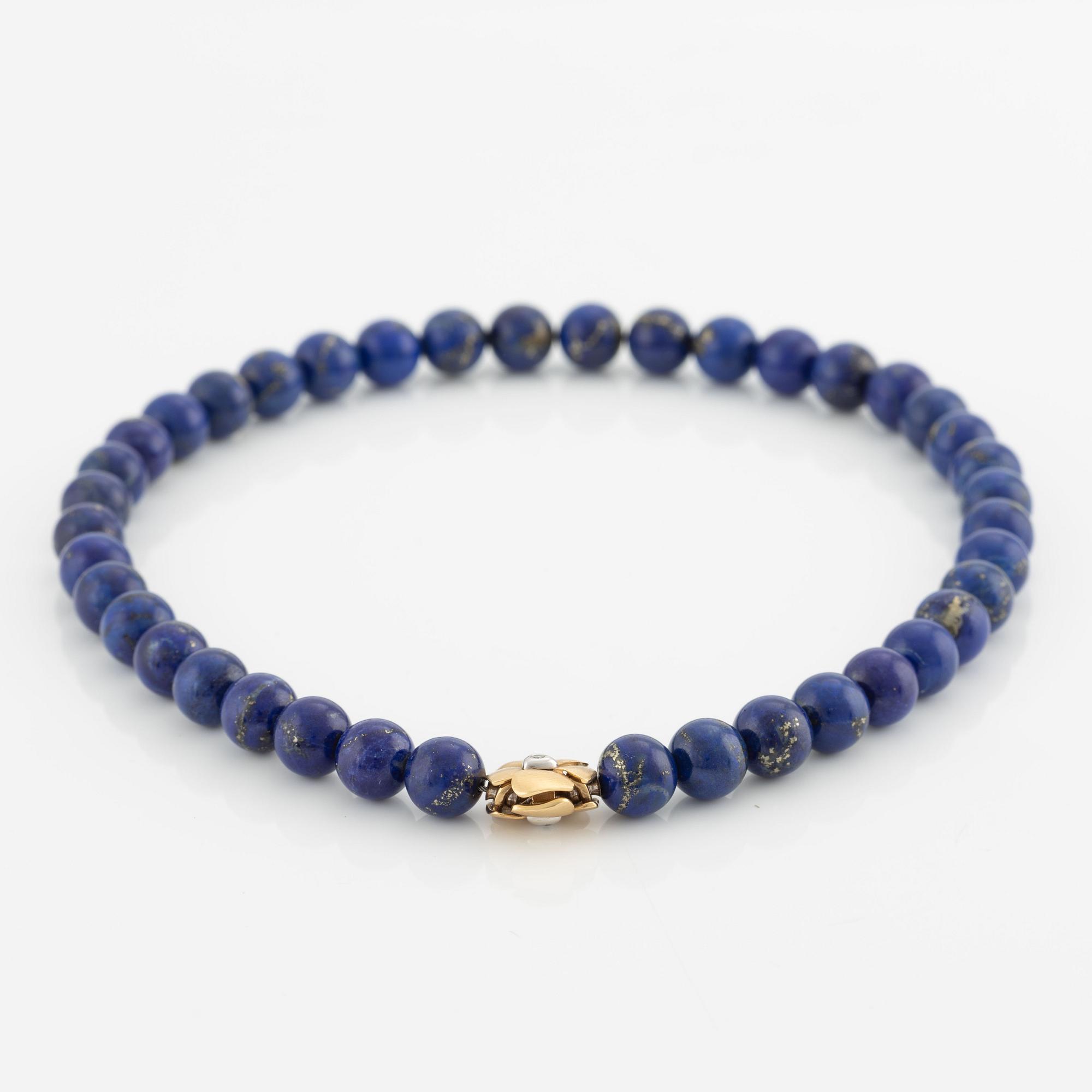 An Ole Lynggaard clasp in 18K gold with round brilliant-cut diamonds and a lapis lazuli necklace.