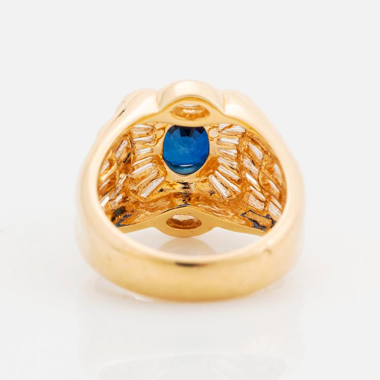 An 18K gold Junod ring set with a facted sapphire and tapered baguette-cut diamonds.