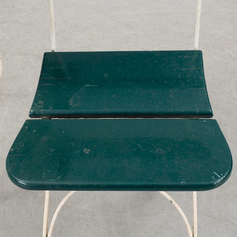 A pair of cast iron chais with wooden seats and a cast iron table, early 20th century.