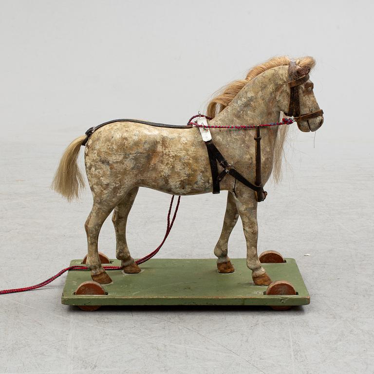 A painted early 20th century toy horse on wheels.