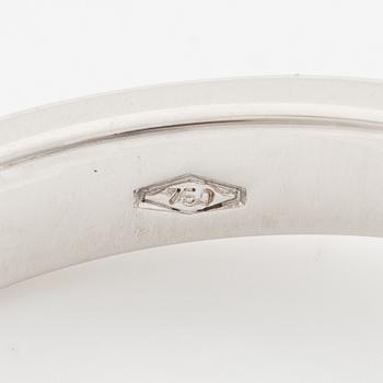 An 18K white gold ring set with an emerald-cut diamond and two step-cut emeralds.