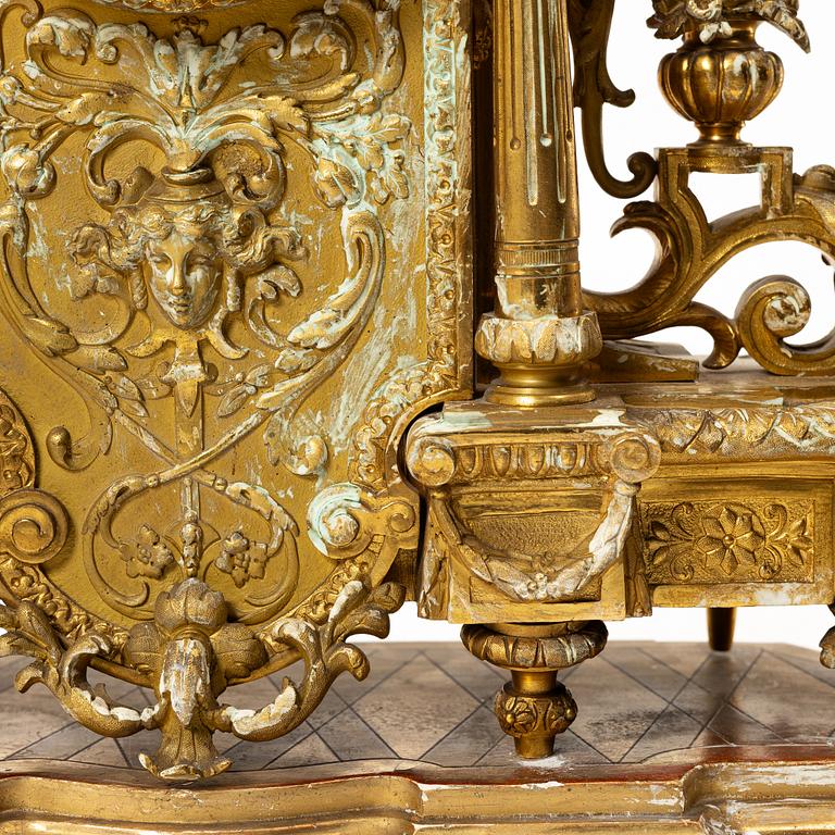 A mantle clock and a pair of candelabra, Louis XVI style, ca 1900.