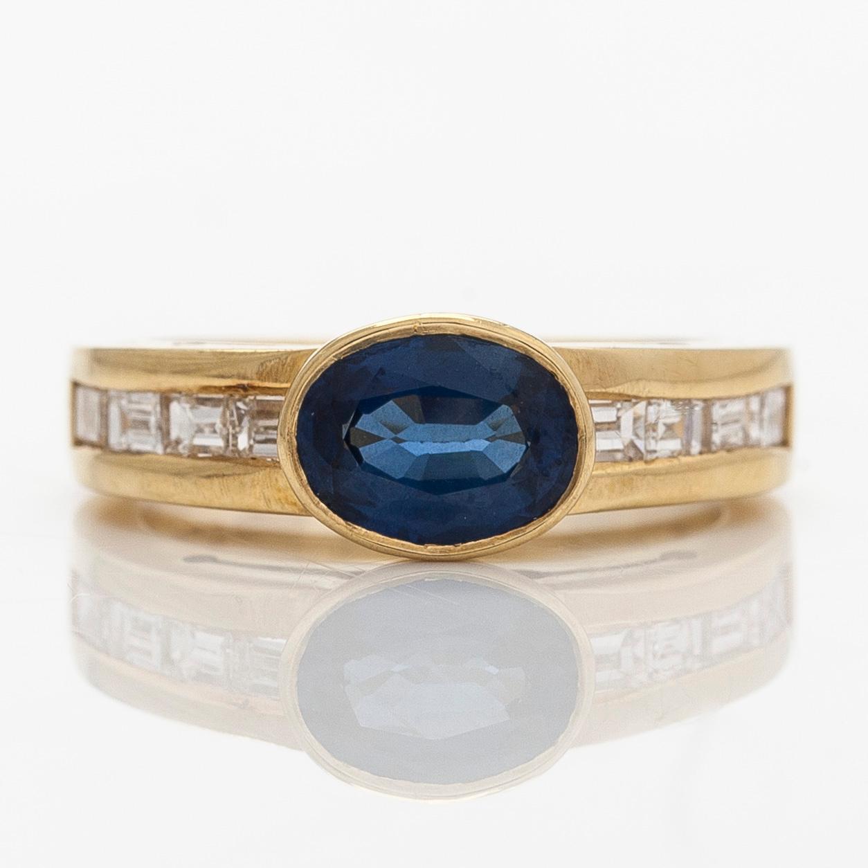 An 18K gold ring with an oval sapphire and baguette-cut diamonds. Finnish hallmarks, year 2000.