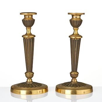 A pair of French Empire patinated and ormolu candlesticks, early 19th century.