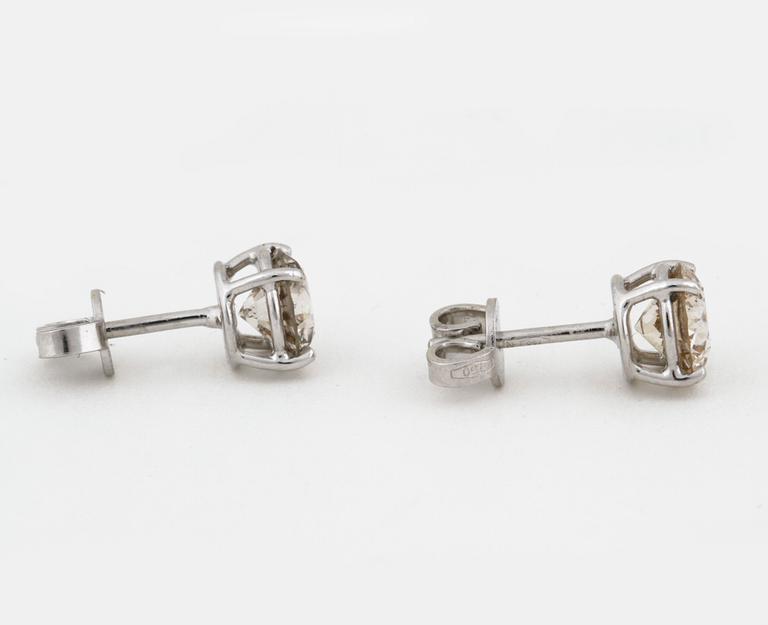 A pair of brilliant cut diamond earrings.