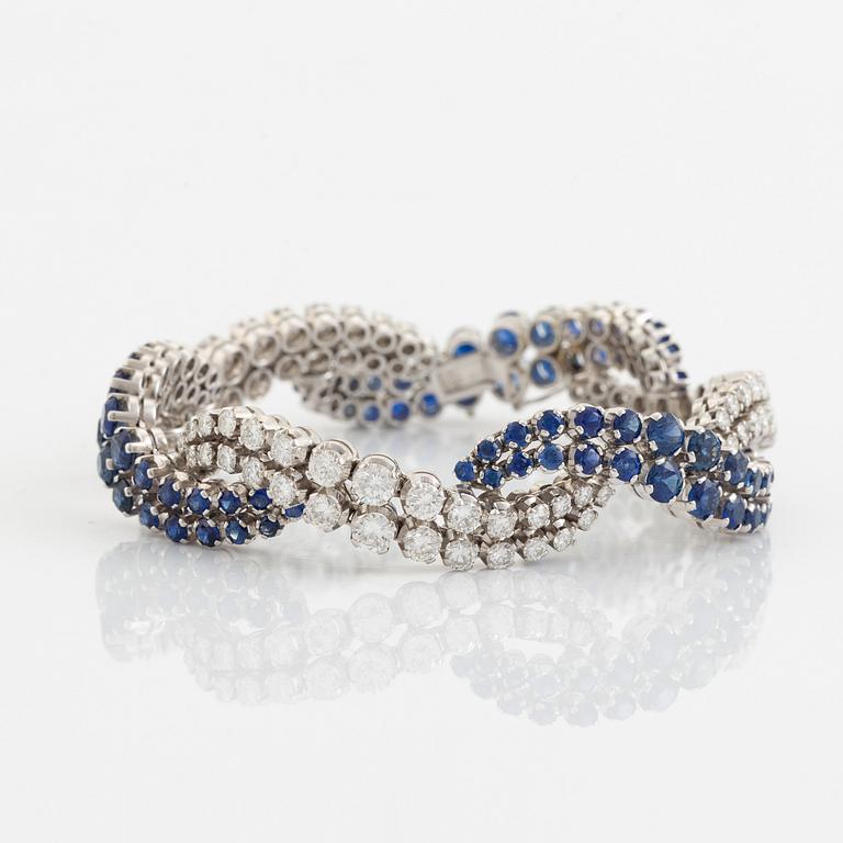 An 18K white gold bracelet set with round brilliant-cut diamonds and sapphires.