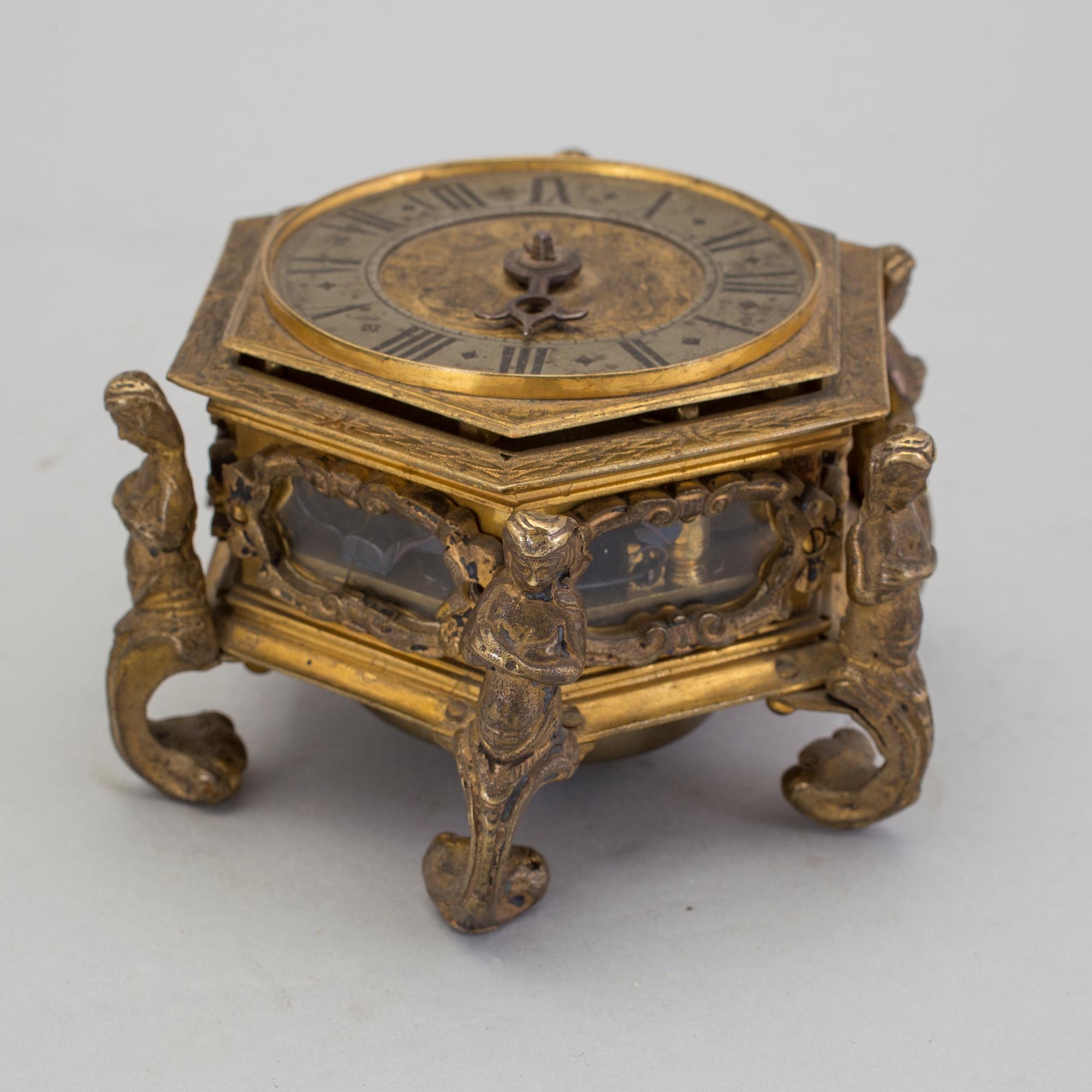 A gilded brass baroque travel clock from around 1700, with original case.