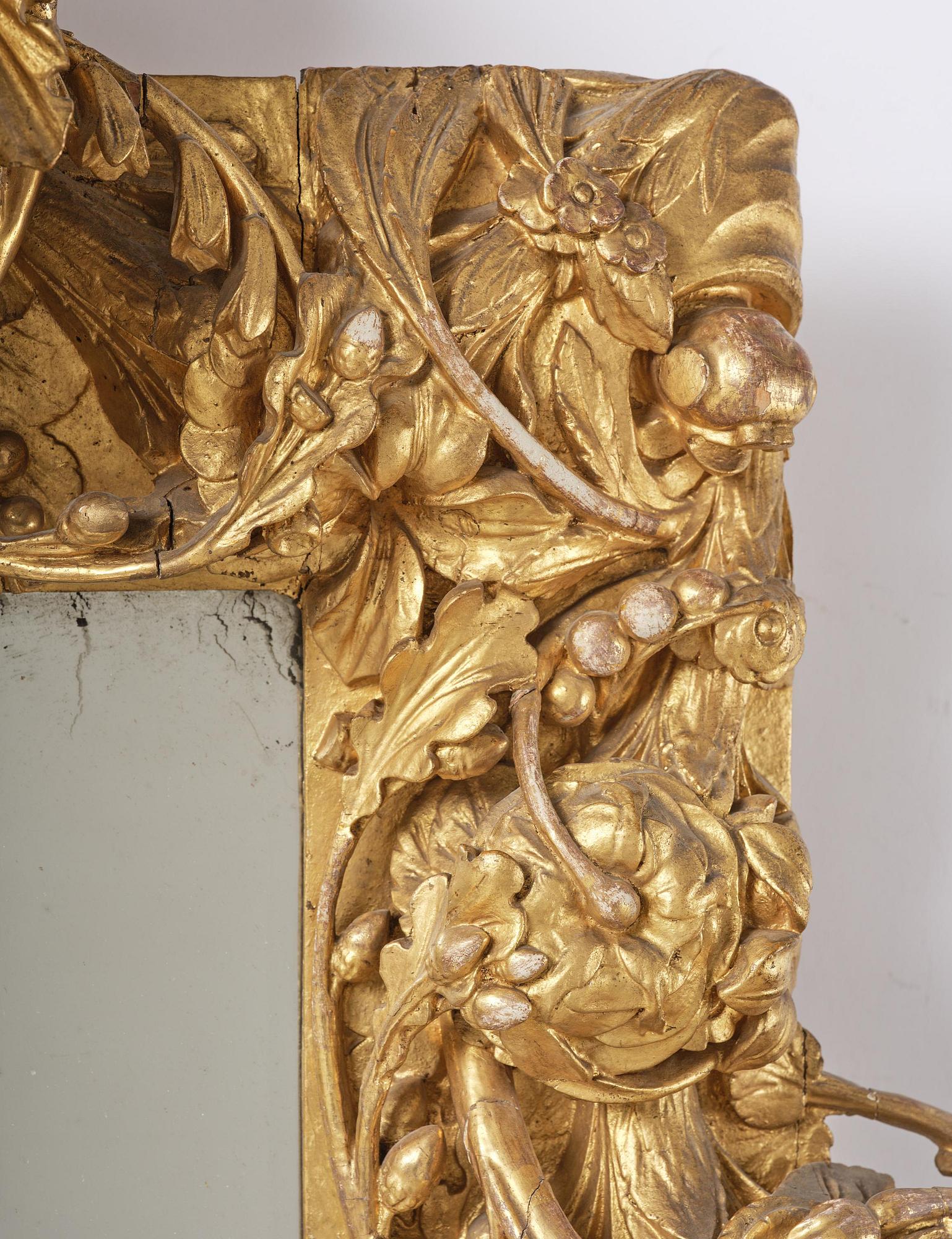 A presumably Dutch Louis XIV carved giltwood frame with mirror glass, in the style of Jean Le Pautre, late 17th century.
