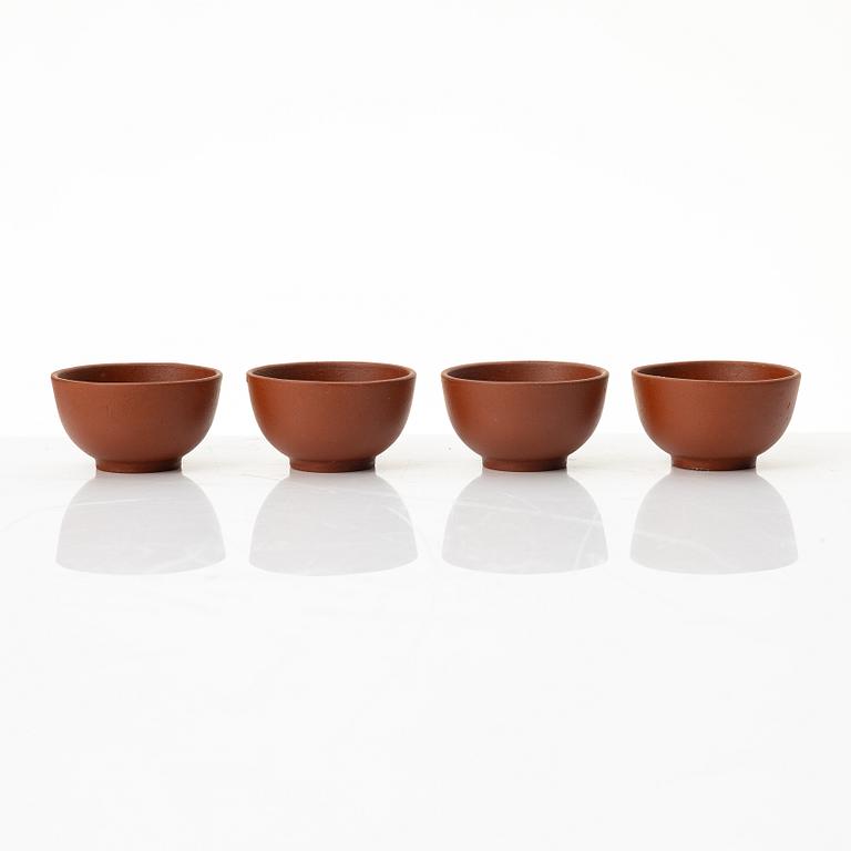 A six part red yixing Gongfu set; teapot, four cups and a tray, China, 1980s.