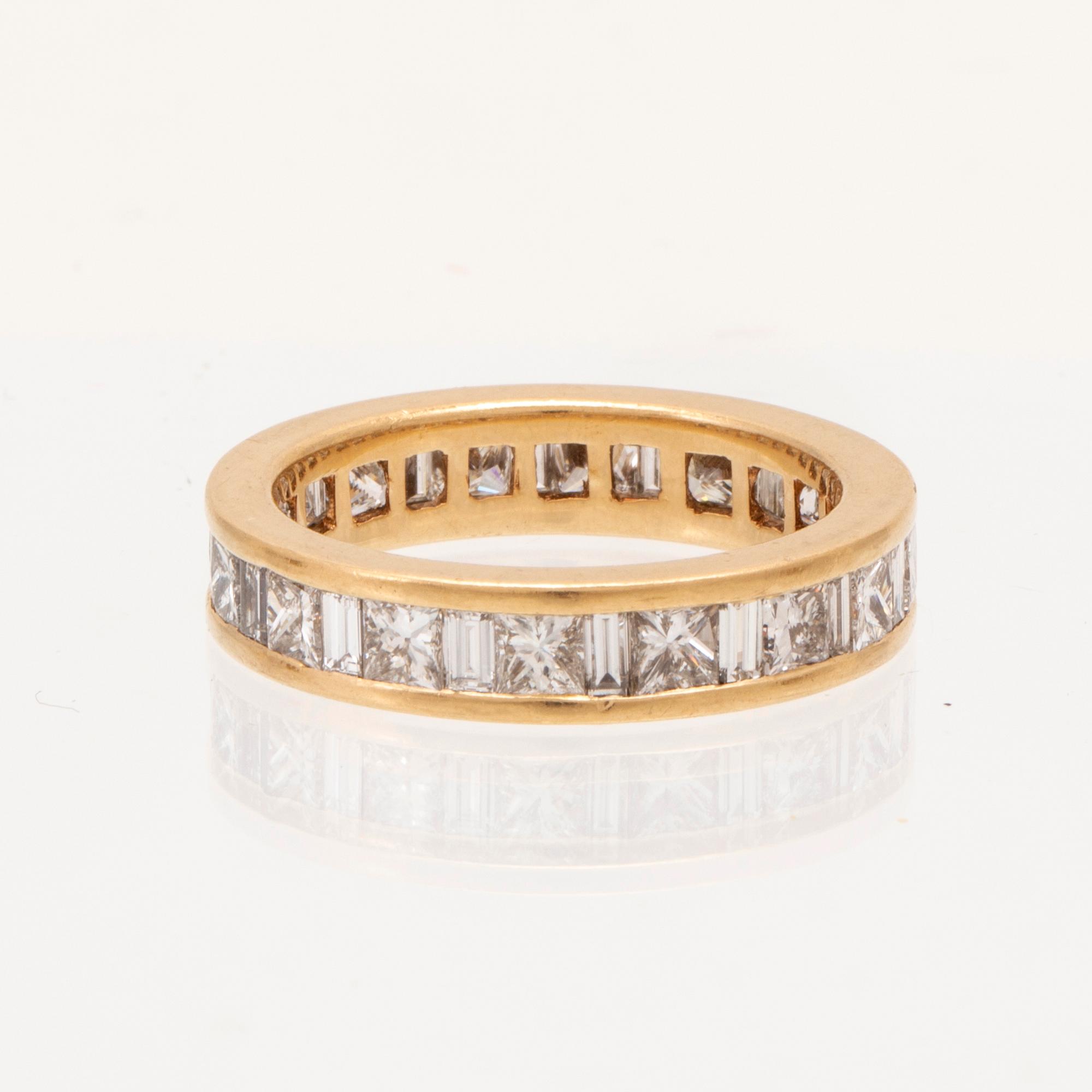 An 18K gold eternity ring set with baguette and princess cut diamonds by Hartmann's Denmark.