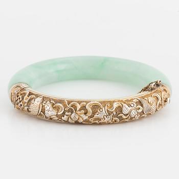 A jade bangle with a gilded silver clasp.