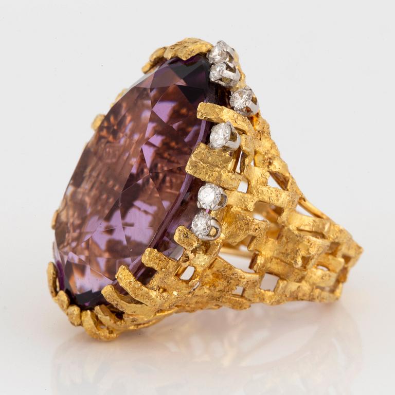An 18K gold and platinum ring set with an amethyst and round brilliant-cut diamonds.