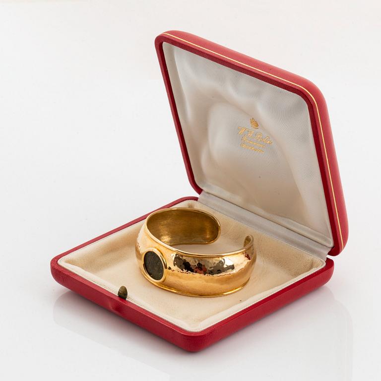 An 18K gold bangle set with an ancient coin.