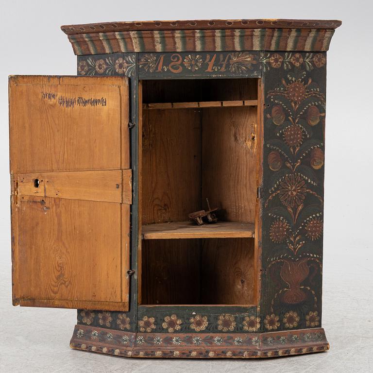A corner hanging cabinet, dated 1844.