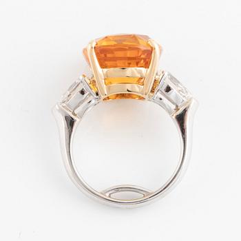 An 18K white gold ring set with a cushion shaped orange-yellow sapphire.