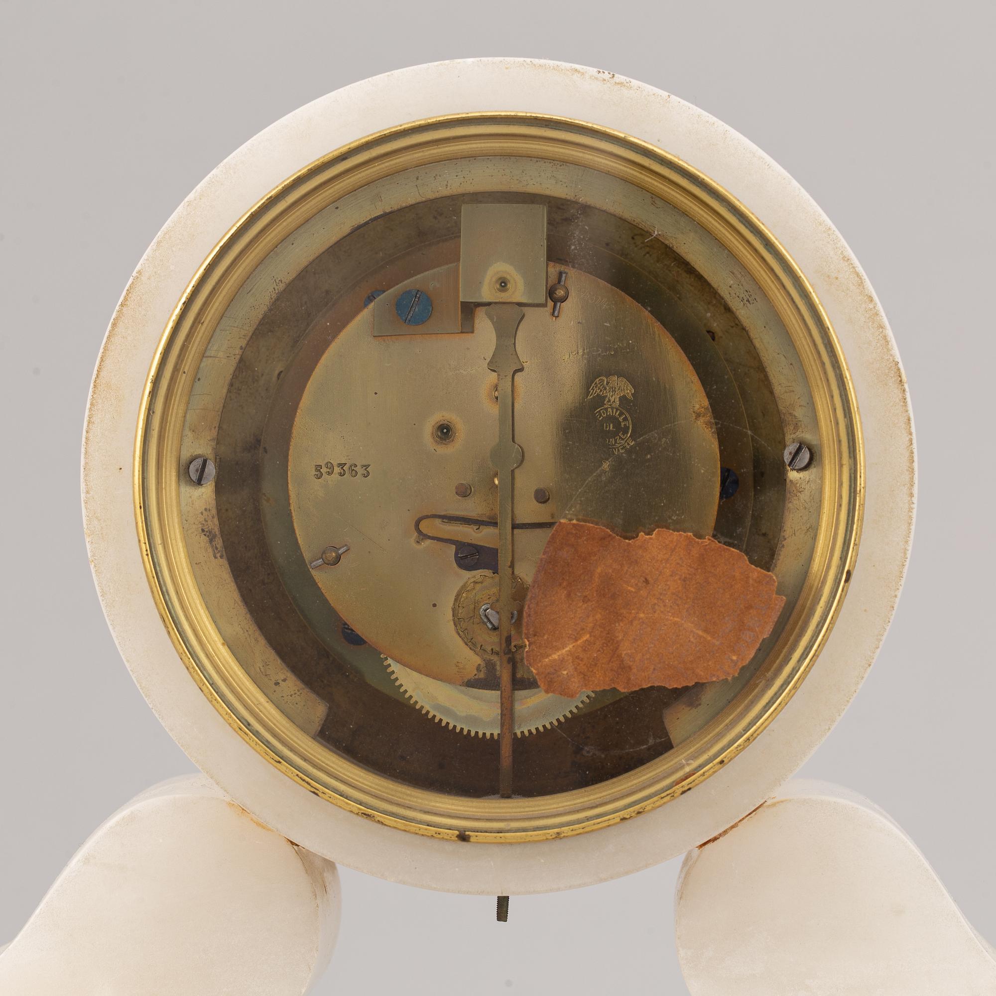 An alabaster mantle clock and pair of candlesticks, circa 1900.