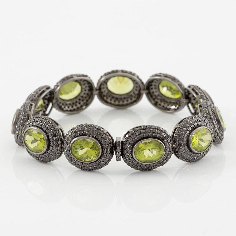 Bracelet in 18K gold with oval peridots and brilliant-cut black diamonds.