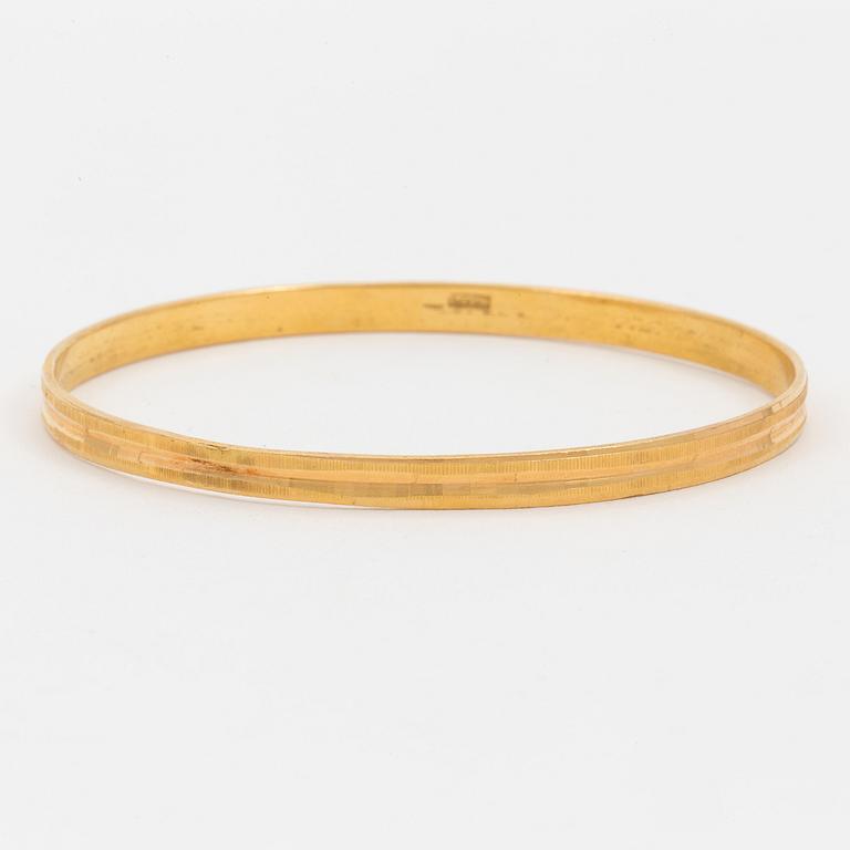 A bangle with a textured surface. 14K gold.
