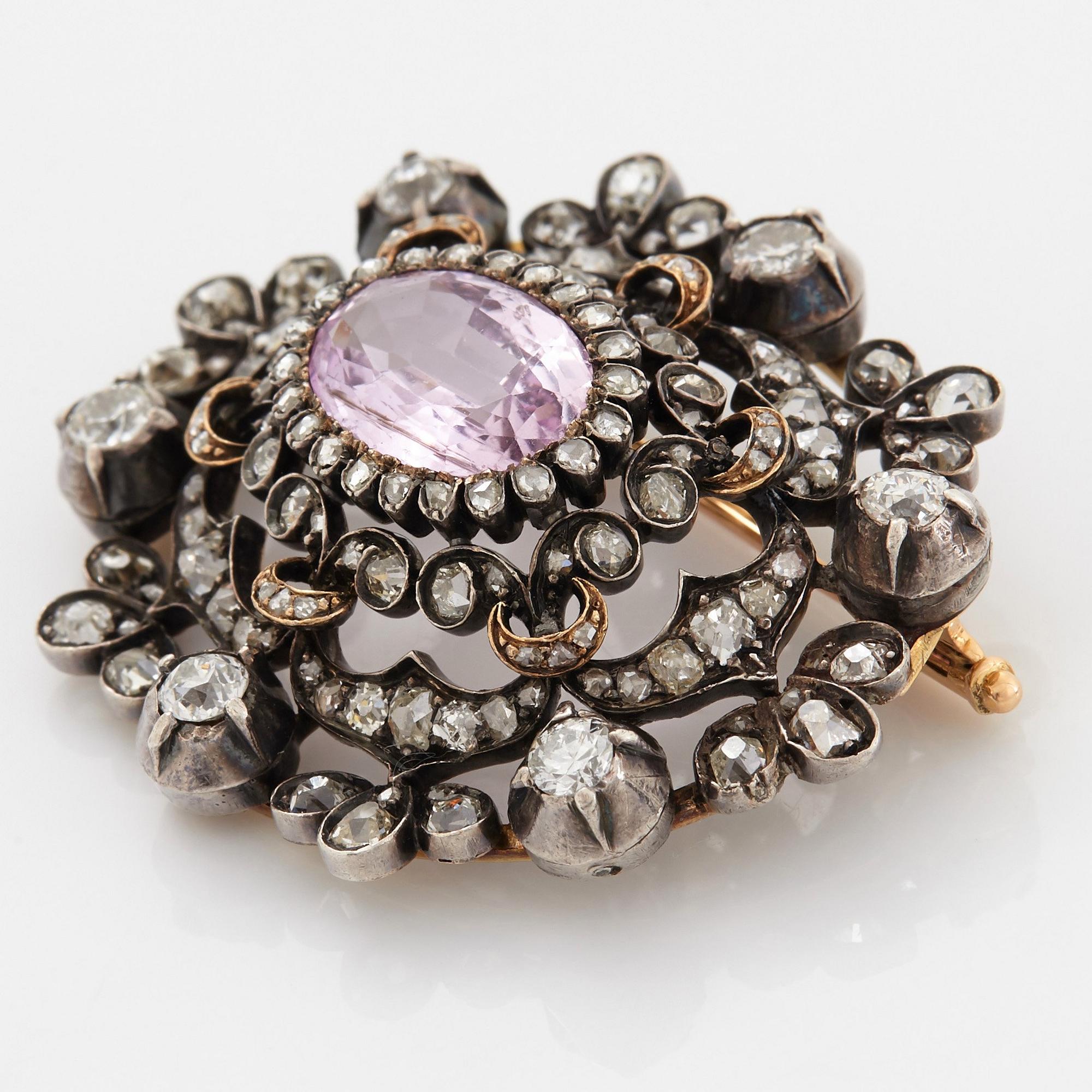 A 14K gold and silver brooch set with an oval faceted pink topaz and old- and rose-cut diamonds.