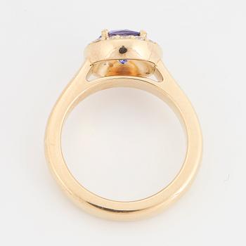 An 18K gold ring set with a faceted tanzanite and round brilliant-cut diamonds.