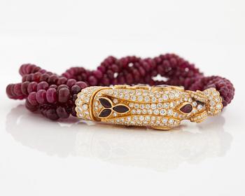 A Cartier chimera head bracelet in 18K gold set with round brilliant-cut diamonds and faceted rubies.