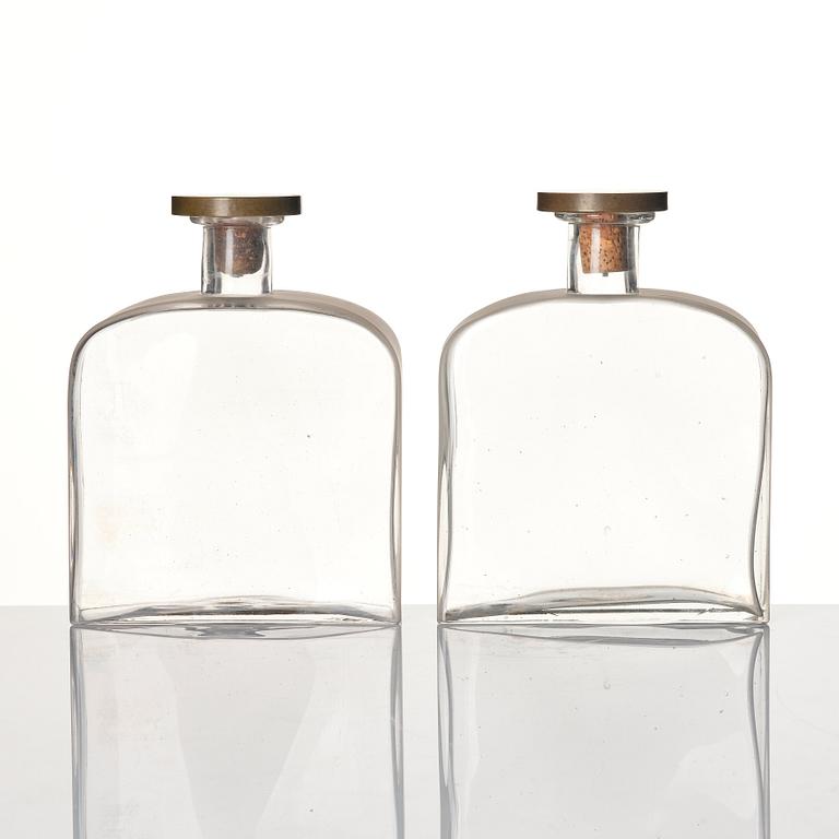 Firma Svenskt Tenn, a pair of glass bottles with pewter and brass stoppers designed by Björn Trägårdh, 1930s.