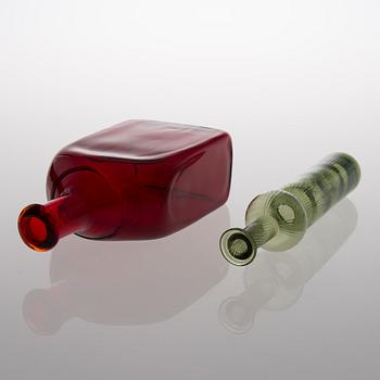 Two glass bottles. A green 'Neptuna' bottle designed by Nanny Still in 1964 and a red bottle from Riihimäen Lasi oy.