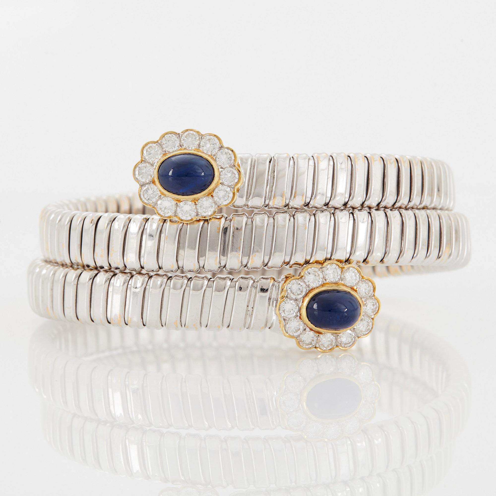An 18K gold bangle set with cabochon-cut sapphires and round brilliant-cut diamonds.